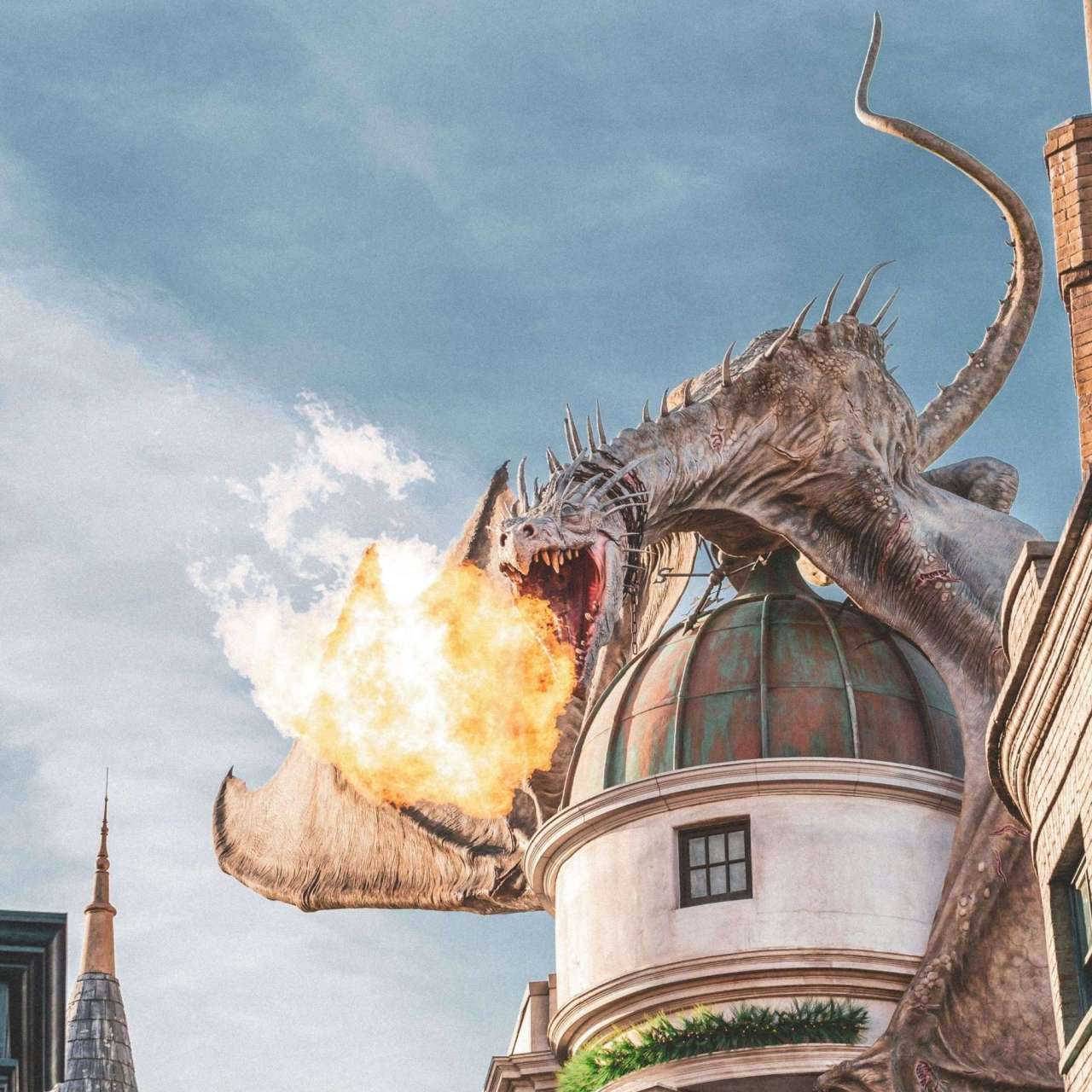 animatronic dragon breathes orange fire atop a castle tower